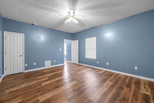 spare room with dark wood-style floors, baseboards, visible vents, and a ceiling fan