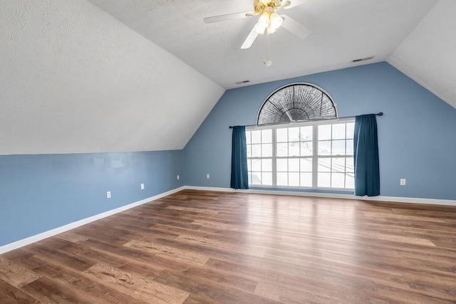 bonus room featuring a ceiling fan, vaulted ceiling, a textured ceiling, wood finished floors, and baseboards