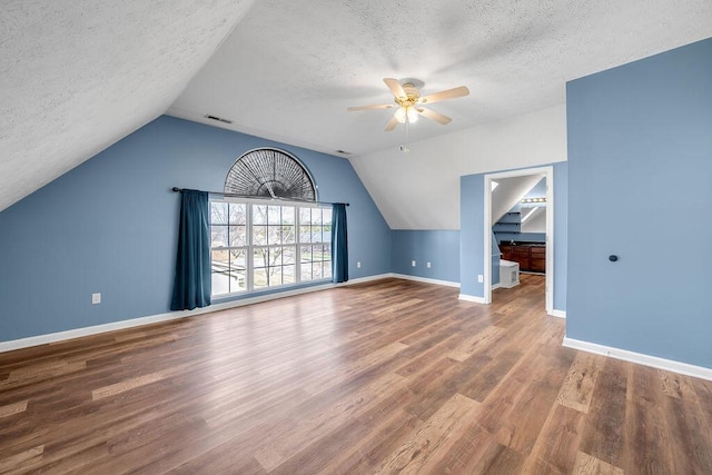 additional living space featuring a textured ceiling, wood finished floors, visible vents, and baseboards