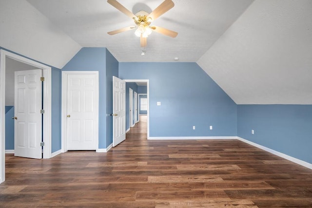 additional living space featuring dark wood-type flooring, vaulted ceiling, baseboards, and a ceiling fan