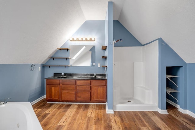 bathroom with vaulted ceiling, double vanity, a sink, and wood finished floors