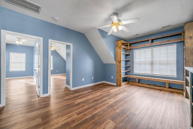 additional living space featuring visible vents, dark wood finished floors, a textured ceiling, and baseboards