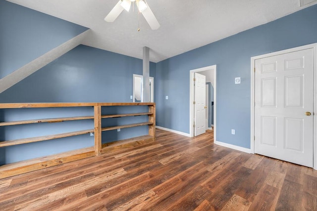 unfurnished bedroom featuring dark wood-type flooring, lofted ceiling, baseboards, and a ceiling fan