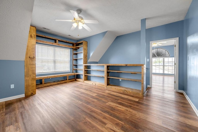 interior space featuring ceiling fan, a textured ceiling, baseboards, and wood finished floors