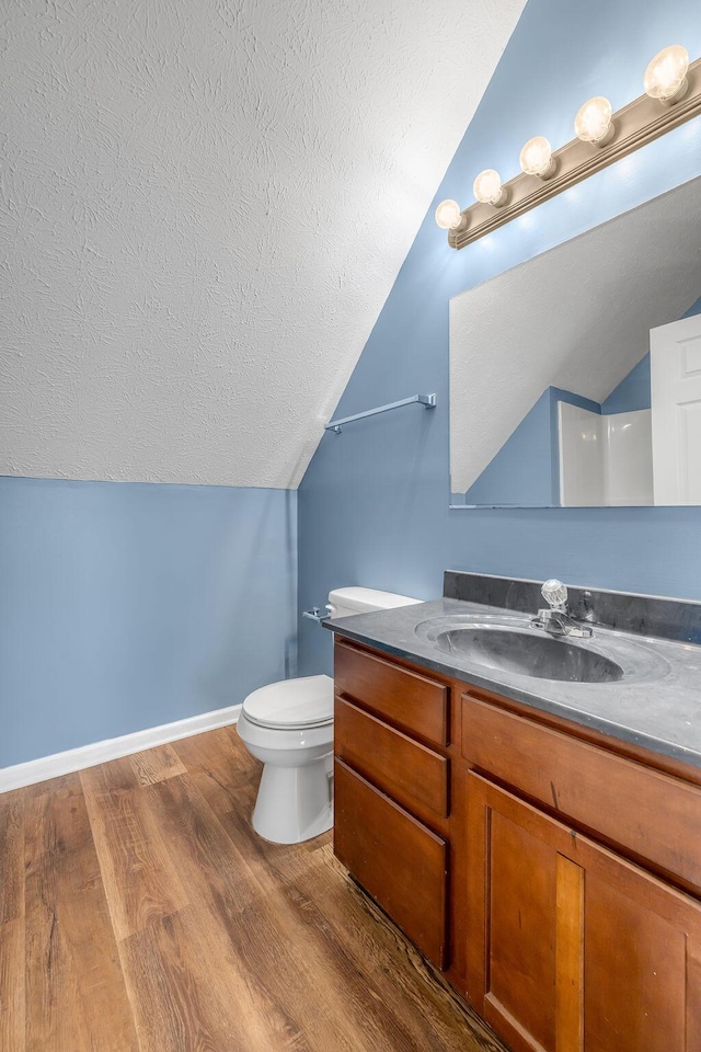 bathroom with toilet, a textured ceiling, vanity, wood finished floors, and baseboards