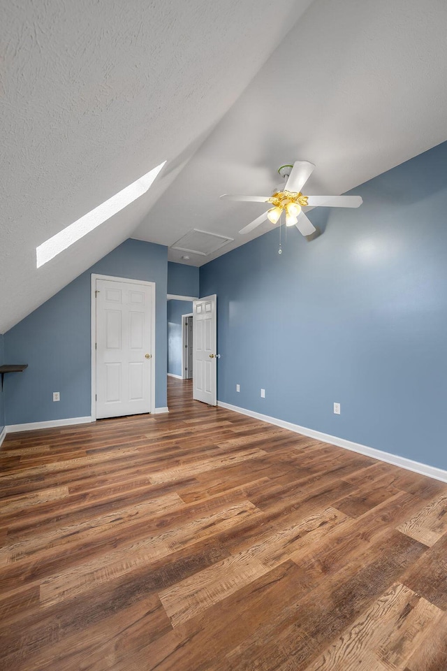 bonus room featuring vaulted ceiling, a textured ceiling, baseboards, and wood finished floors