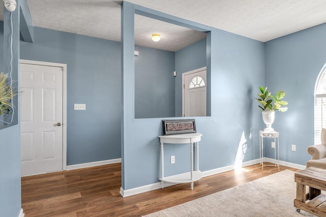 living area with a textured ceiling, baseboards, and dark wood-type flooring