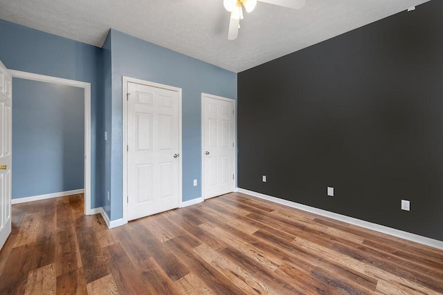 unfurnished bedroom featuring dark wood-style floors, ceiling fan, and baseboards