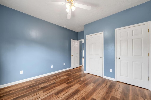 unfurnished bedroom featuring ceiling fan, baseboards, and dark wood-type flooring