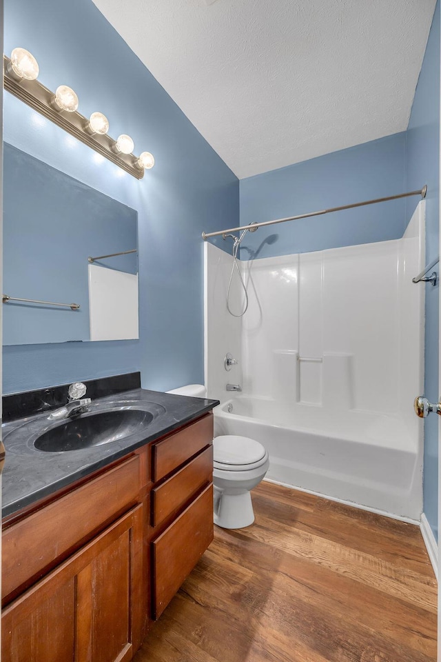 full bathroom featuring a textured ceiling, shower / tub combination, toilet, wood finished floors, and vanity