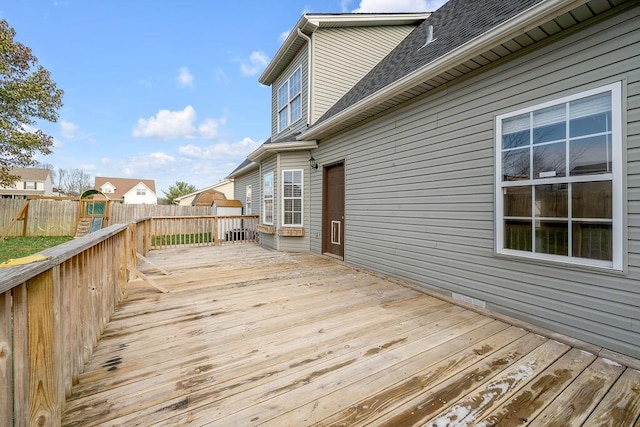 wooden terrace with a playground and fence