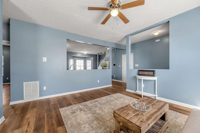 unfurnished living room with baseboards, a textured ceiling, visible vents, and wood finished floors