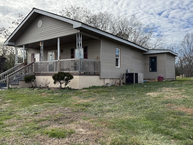 view of front facade featuring covered porch, central AC unit, and a front yard