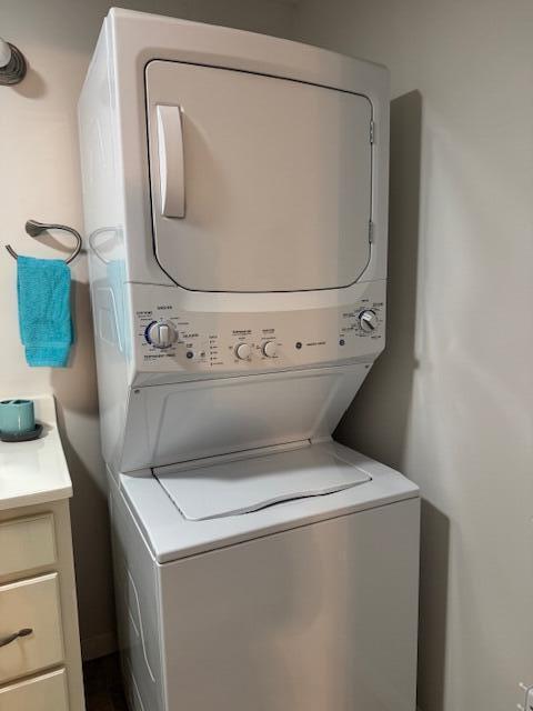 laundry room with stacked washer / dryer and cabinet space