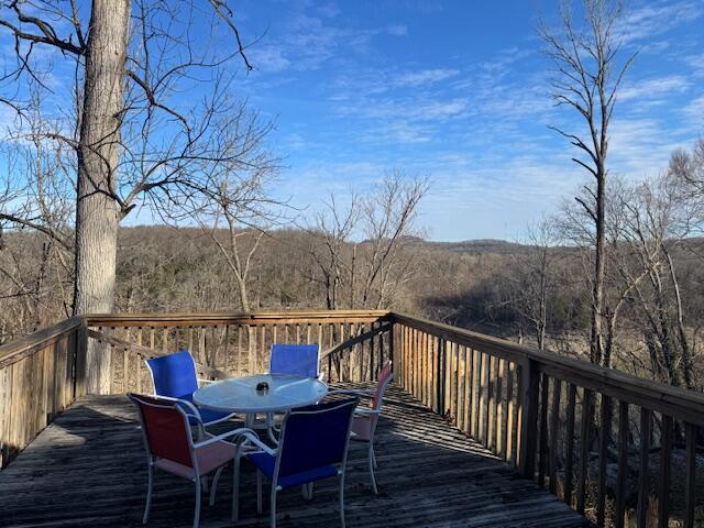 deck with a forest view and outdoor dining space