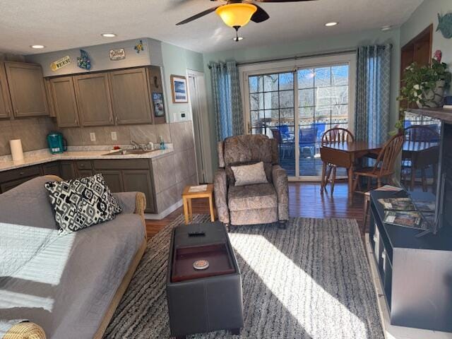 living room featuring dark hardwood / wood-style flooring, ceiling fan, and sink