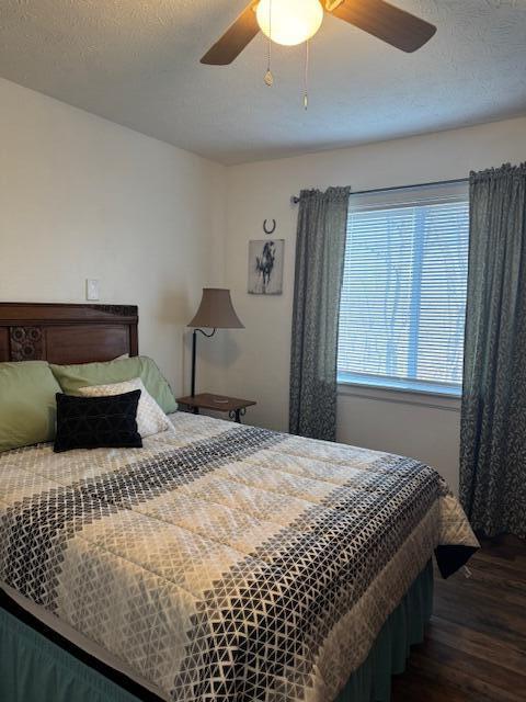 bedroom with ceiling fan, a textured ceiling, and dark wood finished floors