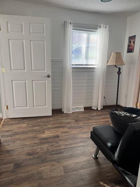 living area with dark wood-style floors, wainscoting, and a textured ceiling