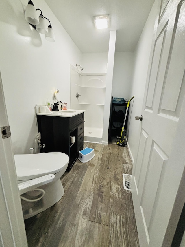 bathroom with wood-type flooring, toilet, walk in shower, and sink