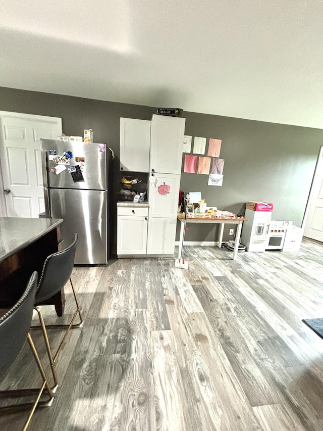 kitchen featuring light wood-type flooring, white cabinetry, and stainless steel refrigerator