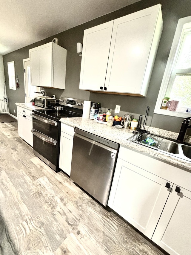 kitchen with white cabinetry, sink, stainless steel appliances, light hardwood / wood-style flooring, and a textured ceiling