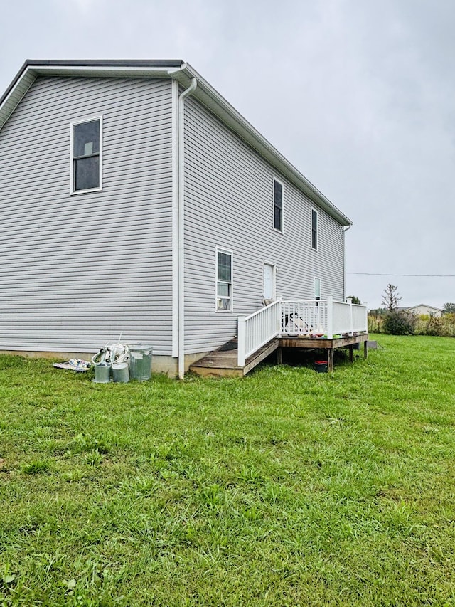 view of side of home featuring a lawn and a wooden deck