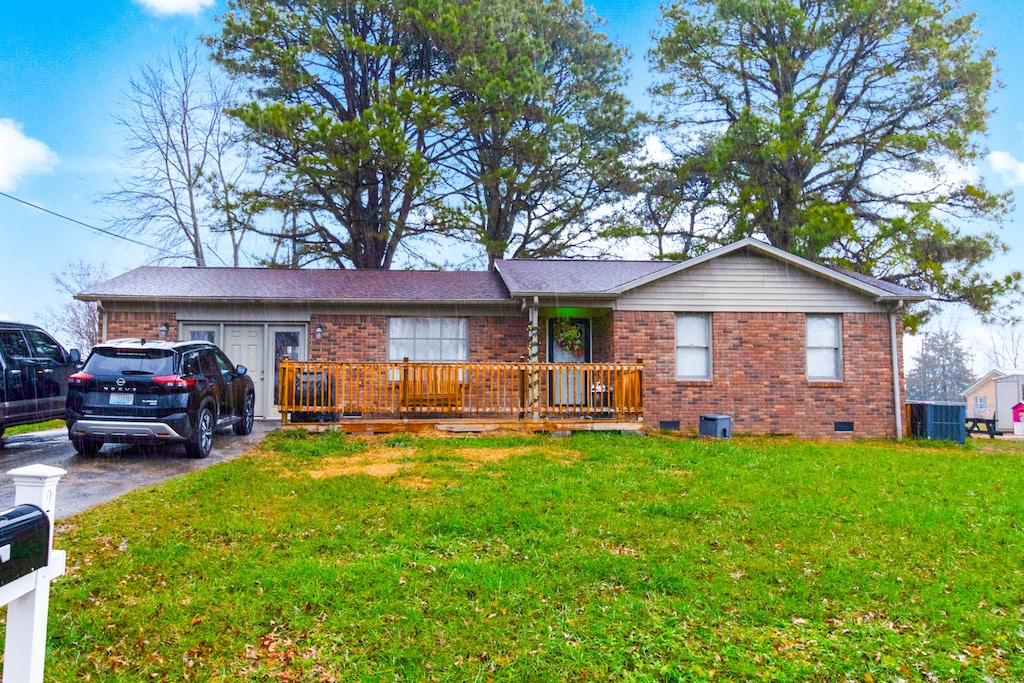 ranch-style home featuring cooling unit and a front yard