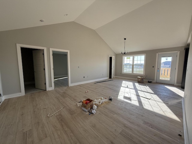 unfurnished living room featuring a chandelier, vaulted ceiling, and light hardwood / wood-style flooring