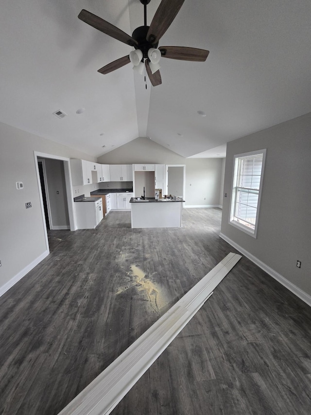 unfurnished living room with ceiling fan, vaulted ceiling, and dark hardwood / wood-style flooring