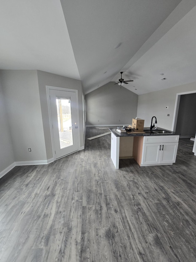 kitchen featuring vaulted ceiling, sink, white cabinetry, dark wood-type flooring, and a kitchen island with sink