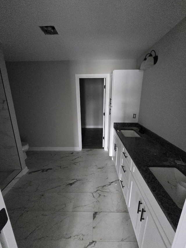 bathroom with a textured ceiling, toilet, and vanity