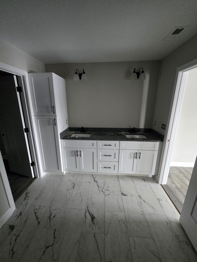 interior space featuring white cabinetry, sink, and a textured ceiling