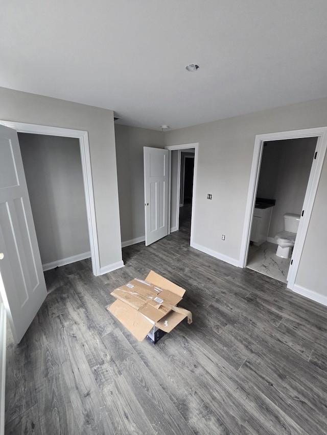 unfurnished bedroom featuring connected bathroom and dark wood-type flooring