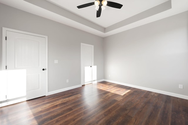 spare room featuring ceiling fan, dark hardwood / wood-style flooring, and a tray ceiling