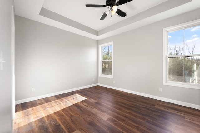 unfurnished room with ceiling fan, a raised ceiling, and dark wood-type flooring