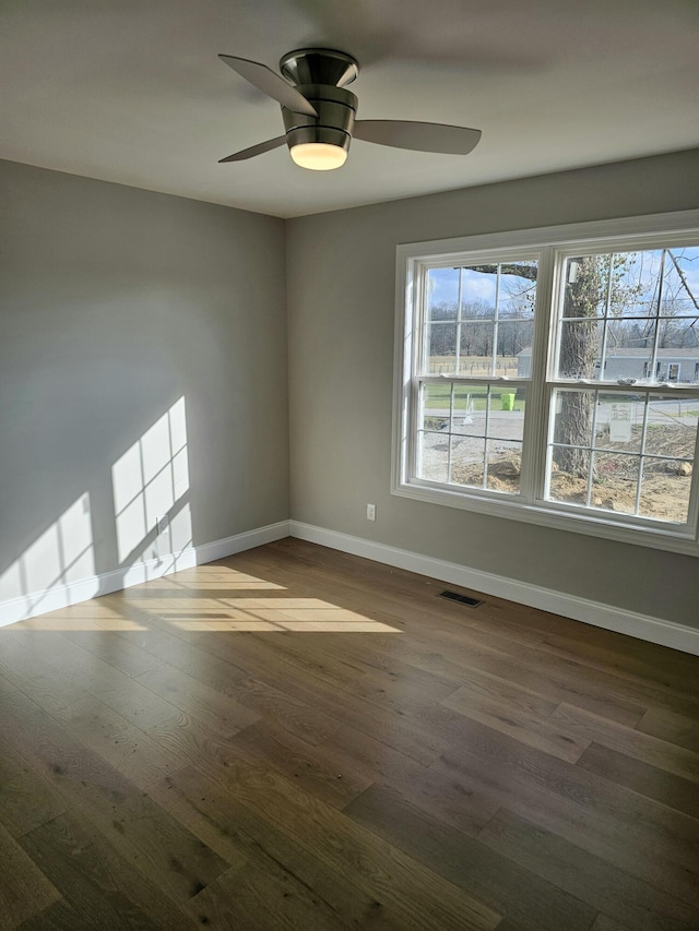 empty room featuring visible vents, baseboards, ceiling fan, and dark wood-style flooring