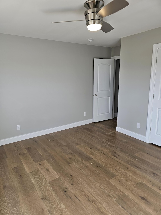 spare room with wood finished floors, a ceiling fan, and baseboards