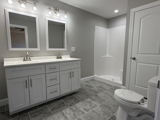 full bathroom with toilet, double vanity, walk in shower, and a sink