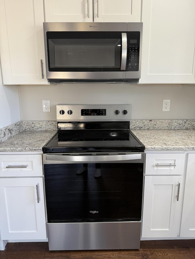 kitchen featuring stainless steel appliances, light stone countertops, and white cabinets