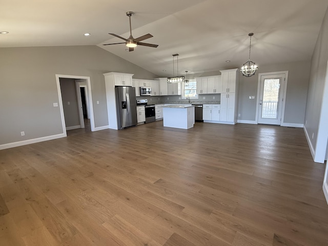 kitchen featuring ceiling fan with notable chandelier, stainless steel appliances, wood finished floors, white cabinets, and open floor plan