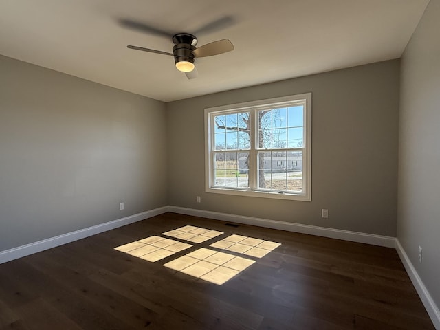 empty room featuring dark wood-type flooring, baseboards, and a ceiling fan