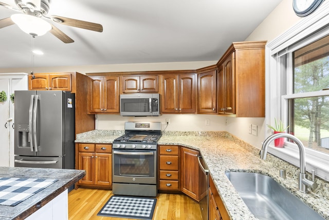 kitchen with stainless steel appliances, light hardwood / wood-style flooring, ceiling fan, and sink