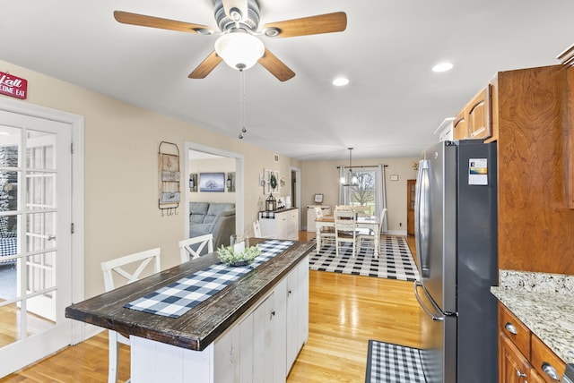 kitchen featuring a center island, stainless steel fridge, light wood-type flooring, and dark stone counters