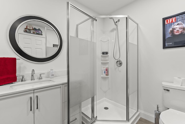 bathroom with a shower with door, vanity, and toilet