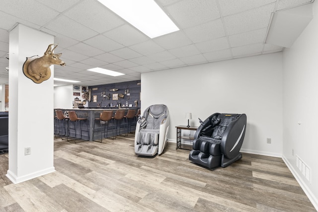 sitting room with hardwood / wood-style flooring, a drop ceiling, and bar area