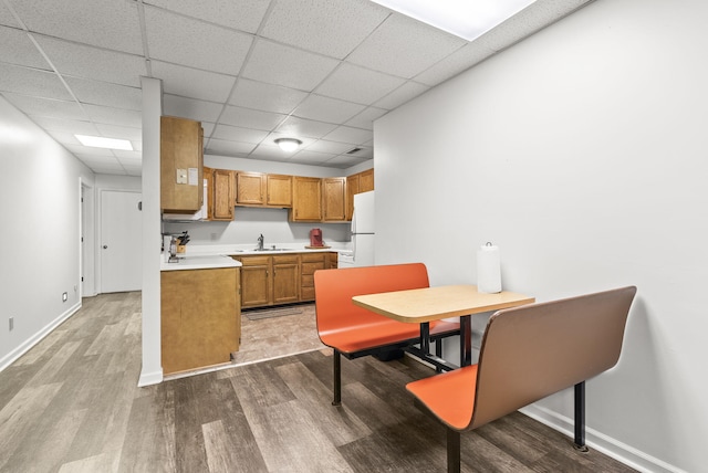 kitchen with a paneled ceiling, white refrigerator, sink, and hardwood / wood-style flooring