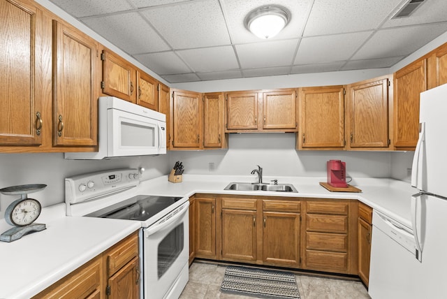 kitchen with white appliances, a drop ceiling, and sink