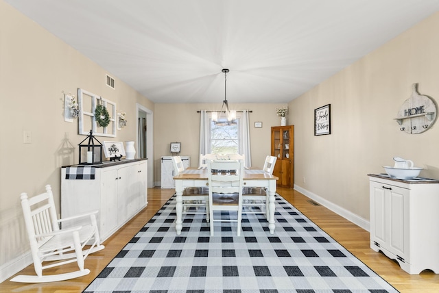 dining area with a chandelier and light hardwood / wood-style floors