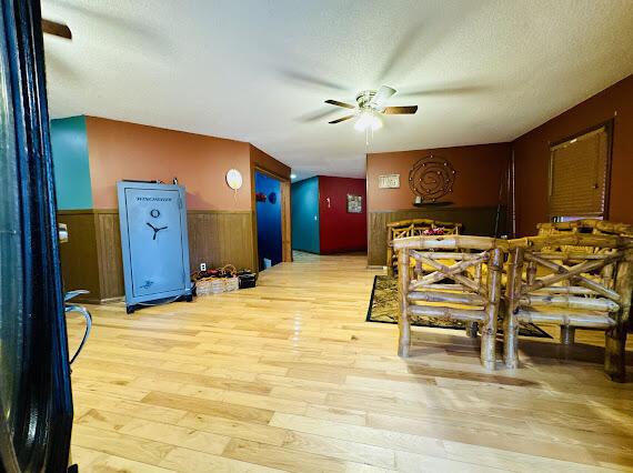 dining area featuring a textured ceiling, light hardwood / wood-style flooring, ceiling fan, and wood walls