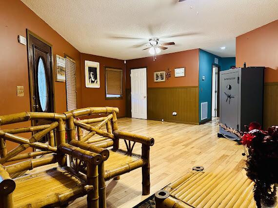 living room with a textured ceiling, light hardwood / wood-style flooring, and ceiling fan